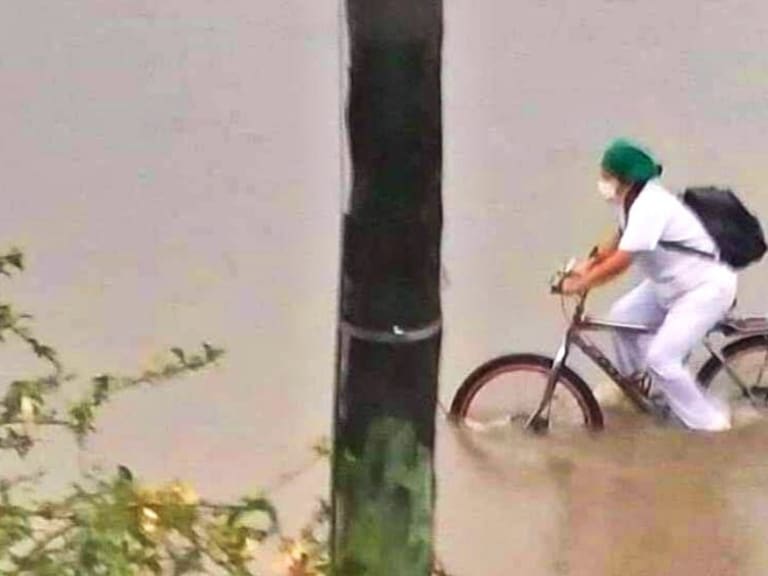 Enfermera en bicicleta pasa por calles inundadas para poder llegar a casa