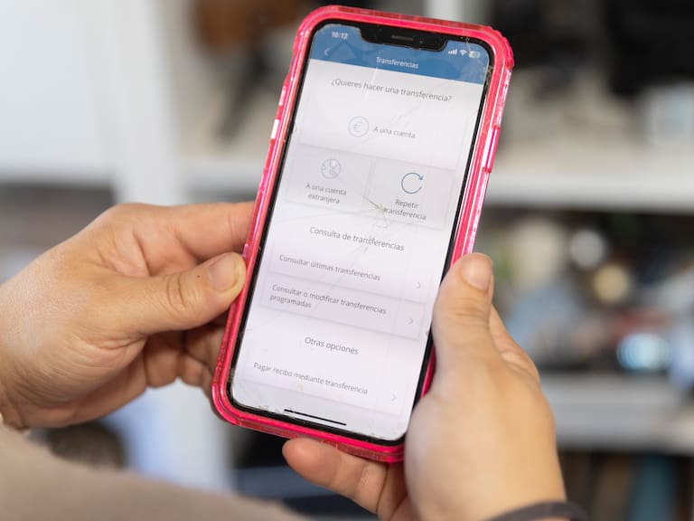 Una mujer realiza una transferencia bancaria con su teléfono.