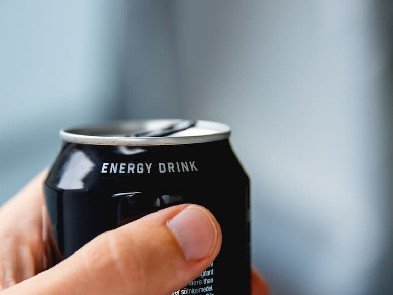 close up of a hand holding a can of energy drink