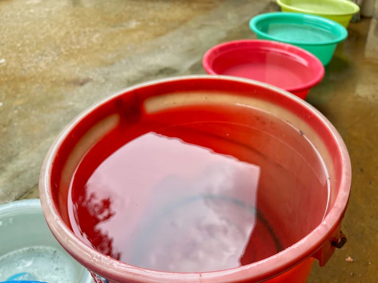 Close-up of a row of colorful pails with collected rain water as part of recycling effort