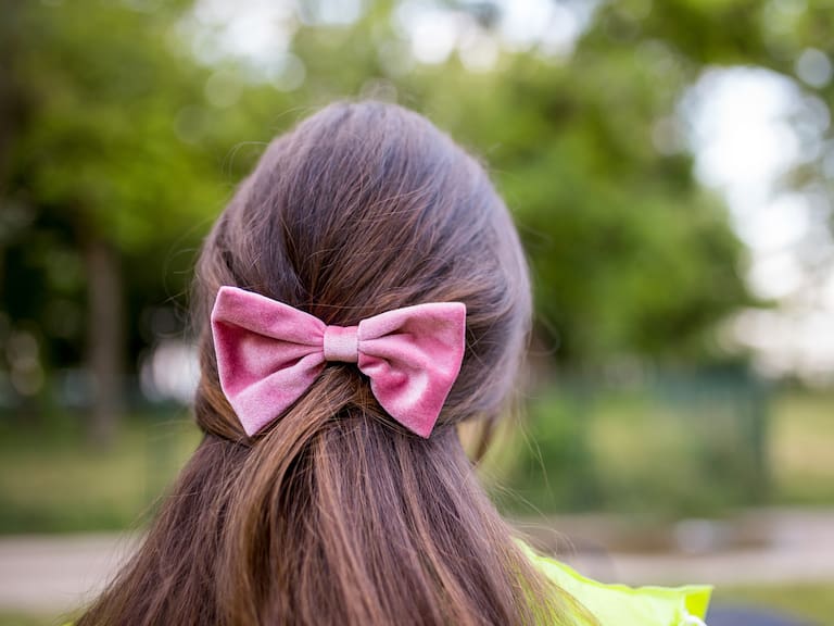 Photo of a beautiful girl with long hair and a bow on her head.