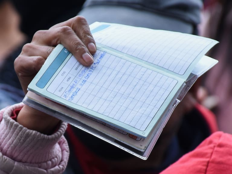 Una mujer muestra su carnet para mostrar el día de su cita.