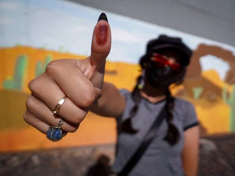 Una mujer muestra su pulgar pintado de tinta tras emitir su voto.