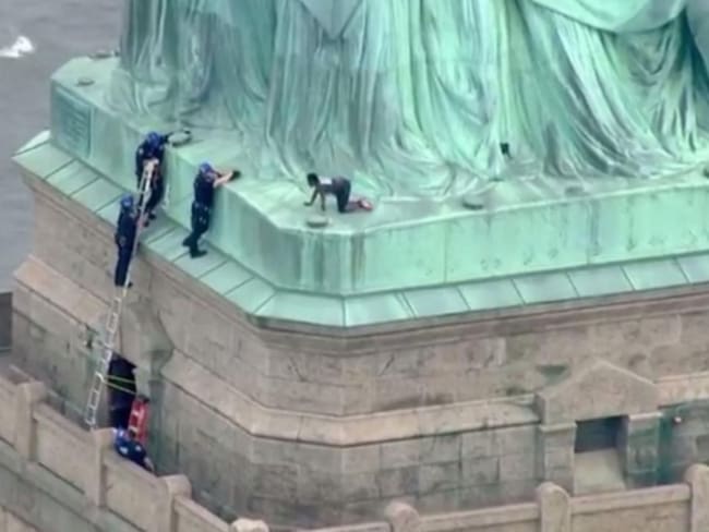 Mujer escala la Estatua de la Libertad contra Donald Trump