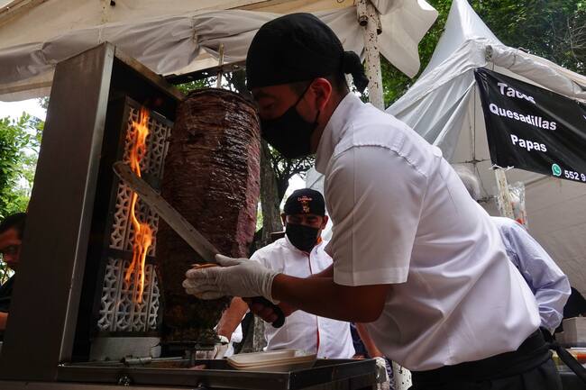 Taquero cortando un trompo de pastor