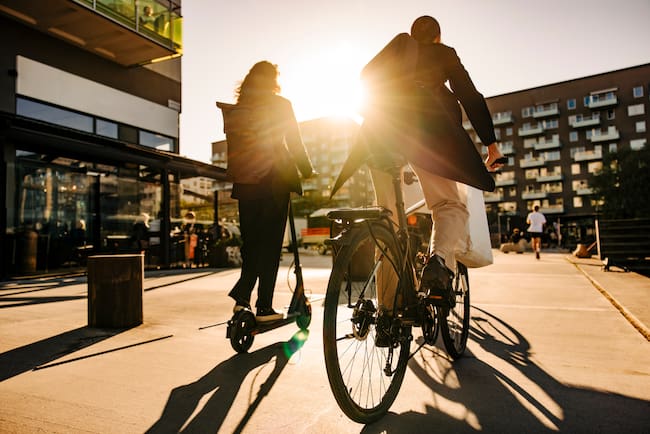 Mujer y hombre conduciendo scooter y bicicleta eléctrica.