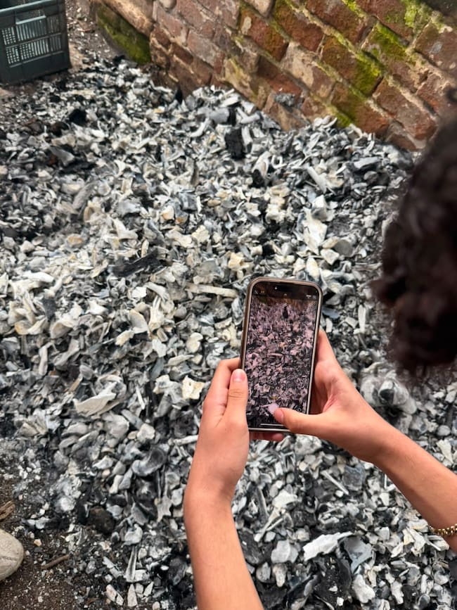 Integrante de Madres Buscadoras toma fotografía a pila de presuntos fragmentos óseos calcinados en supuesto crematorio clandestino en Jalisco.