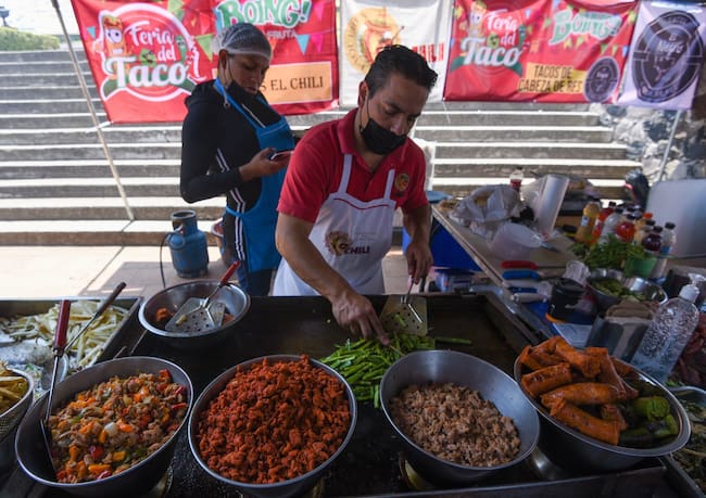 Taquero con diferentes carnes e ingredientes para hacer tacos